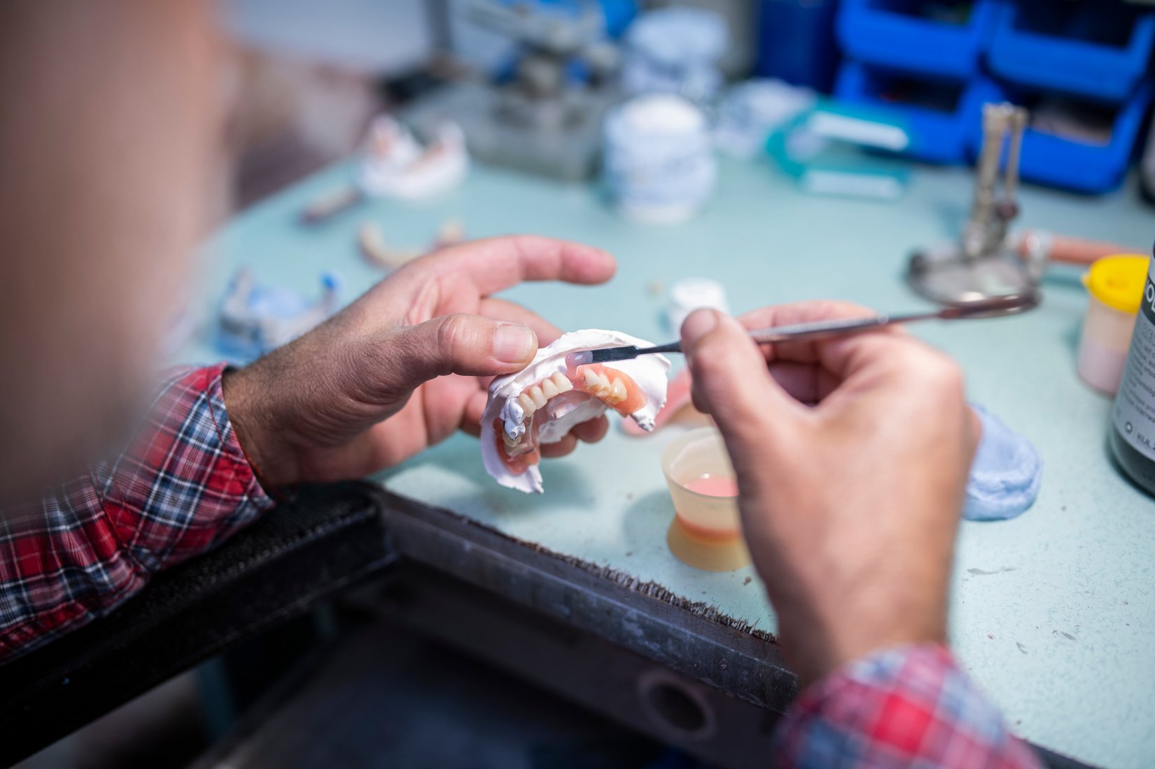 A prosthodontist working on dentures, dental technician repair dentures.